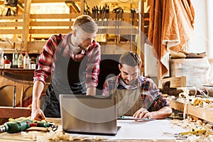 Carpenters with laptop and blueprint at workshop