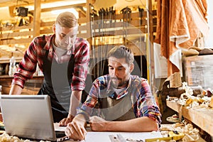 Carpenters with laptop and blueprint at workshop