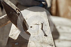 Carpenters uses a hammer to driving nail, Craftsmen and builder equipment. A man hammers an iron nail into a wooden beam