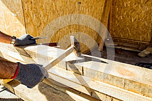 Carpenters uses a hammer to driving nail, Craftsmen and builder equipment. A man hammers an iron nail into a wooden beam