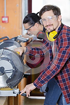 carpenters using circular saw in workshop