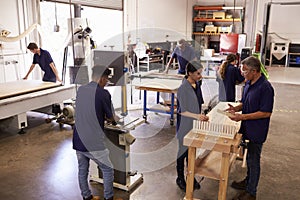 Carpenters Working On Machines In Busy Woodworking Workshop