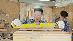 Carpenters are working in a wood factory. Carpenter is using a meter to measure wood sizes. Water level meter.