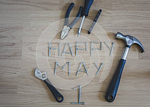 Carpentery tools placed on wooden floor with happy mady first written with arragement of screws