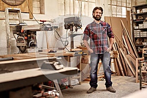 Carpentry business owner standing in his workshop with machinery