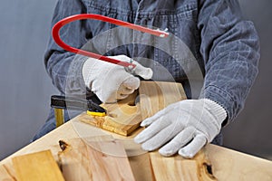 Carpentry Concepts. Hands of Carpenter in Apron Working With Fret-Saw and on Wooden Construction
