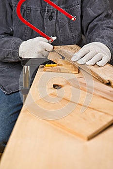 Carpentry Ideas. Hands of Carpenter in Apron Working With Fret-Saw and Screw-driver on Wooden Construction