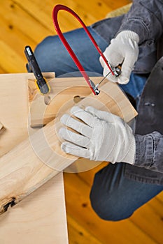 Carpentry Ideas. Hands of Carpenter in Apron Working With Fret-Saw and Screw-driver on Wooden Construction