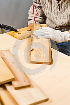 Carpentry Ideas. Hands of Carpenter in Apron Working With Fret-Saw and Screw-driver on Wooden Construction Background