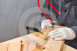 Carpentry Ideas. Hands of Carpenter in Apron Working With Fret-Saw and Screw-driver on Wooden Construction Background