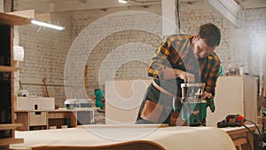 Carpentry industry - man cutting a small piece of wood using big circular saw