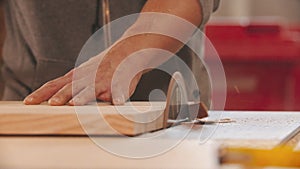 Carpentry industry - man worker cutting a small piece of wood using big circular saw