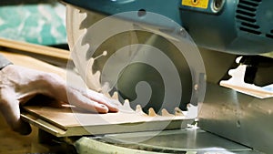 Carpentry - a man woodworker cutting the wooden detail with a sharp circular saw. low light. color