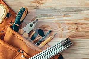 Carpentry tool belt on woodwork workshop desk, top view