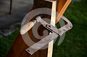 Carpentry work cannot do without a metal clamp with a screw-on wooden handle holding the board on the beam firmly and professional