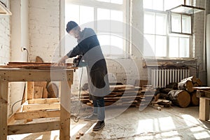 Carpentry workshop. Man using electric hand saw on wooden planks