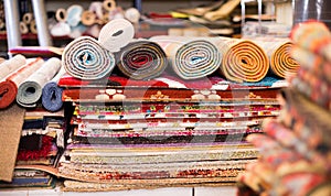 Carpets of different colours in stack at carpet store