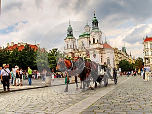 Carriage with horses and St. Nicholas church in the Old Town Square in Prague, Czech Republic