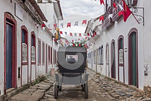 A carriage in a street adorned with flags for the Divine Holy Spirit Festivity in Paraty, Brazil.