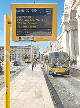 Carris bus in Lisbon approaching the stop with information panel on waiting times.