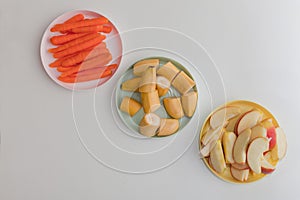 carrot, apple and banana slices on the plates, fresh vegetables and fruits