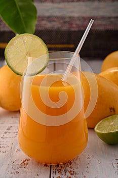 Carrot beverage macro with lime on white vintage wooden desktop with mangos