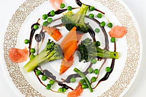 Carrot,broccoli,peas and ginger in balsamico circle on white plate.