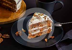 Carrot cake with butter cream and walnuts on a dark background