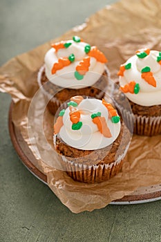 Carrot cake cupcakes with cream cheese frosting decorated with little carrots