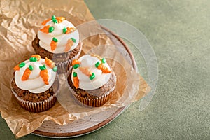 Carrot cake cupcakes with cream cheese frosting decorated with little carrots