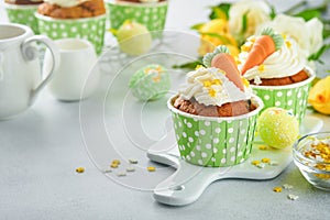 Carrot cake cupcakes for Easter. Carrot cupcakes with cream cheese frosting decorated with tiny marzipan carrots