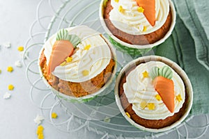 Carrot cake cupcakes for Easter. Carrot cupcakes with cream cheese frosting decorated with tiny marzipan carrots on white