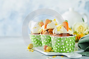 Carrot cake cupcakes for Easter. Carrot cupcakes with cream cheese frosting decorated with tiny marzipan carrots on white
