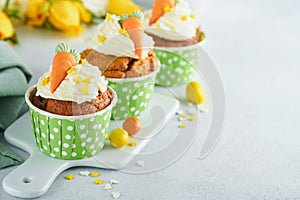 Carrot cake cupcakes for Easter. Carrot cupcakes with cream cheese frosting decorated with tiny marzipan carrots on white backgro