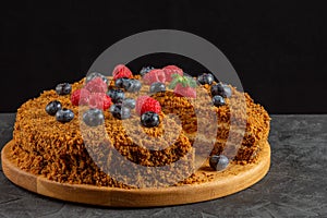 carrot cake decorated with blueberries and raspberries on a dark background