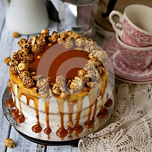 Carrot cake with salted caramel and cheesecake inside, decorated with popcorn and caramel. Retro style, vintage. Selected focus,