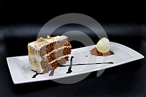 Carrot Cake on a white plate with ice cream on a black background