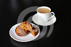 Carrot cakes with walnuts and spices, next to a white porcelain Cup of green tea