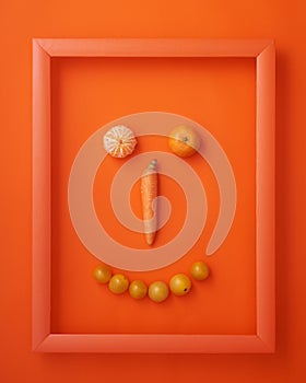 Carrot, cherry tomatoes and clementines in frame on orange