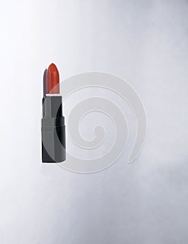 Carrot-colored vertical lipstick lies on a white background open without a cap in a black case photo
