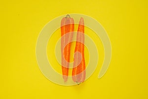 Carrot cut in half on yellow background. Healthy vegetarian food