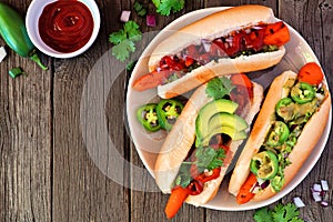 Carrot hot dogs with assorted toppings, top view table scene with a wood background