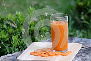 Carrot juice and carrot segments on a wooden background