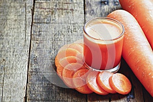 Carrot juice and carrot slices on wood table