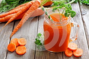 Carrot juice in a mason jar, still life over rustic wood