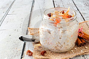 Carrot overnight oats with nuts and raisins in a mason jar on white wood