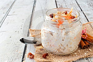 Carrot overnight oats with nuts and raisins in a mason jar on white wood photo