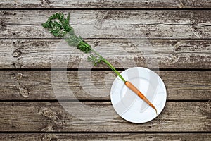 Carrot on a plate on rustic wooden table.