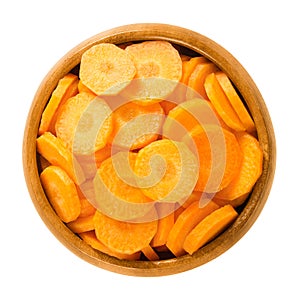 Carrot slices in wooden bowl over white