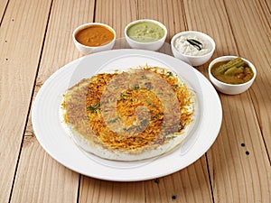 Carrot Uthappam with sambar and chutneys served in a plate on wooden background